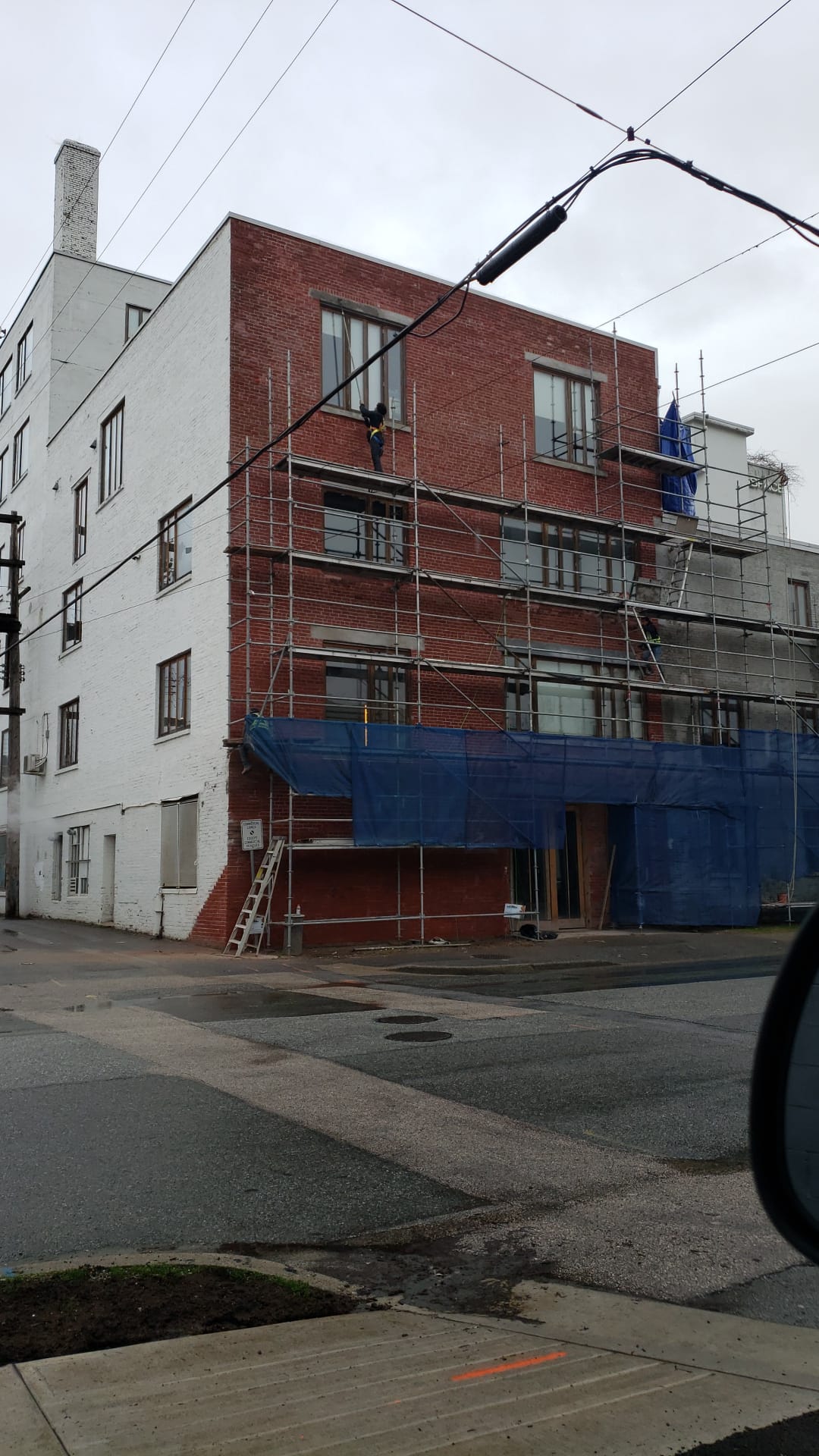 Mason working from scaffold on upper facade — Living Spaces