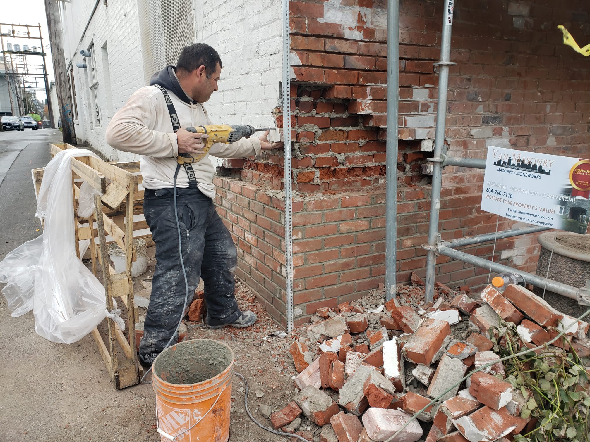 Mason removing deteriorated brick from the facade — Living Spaces