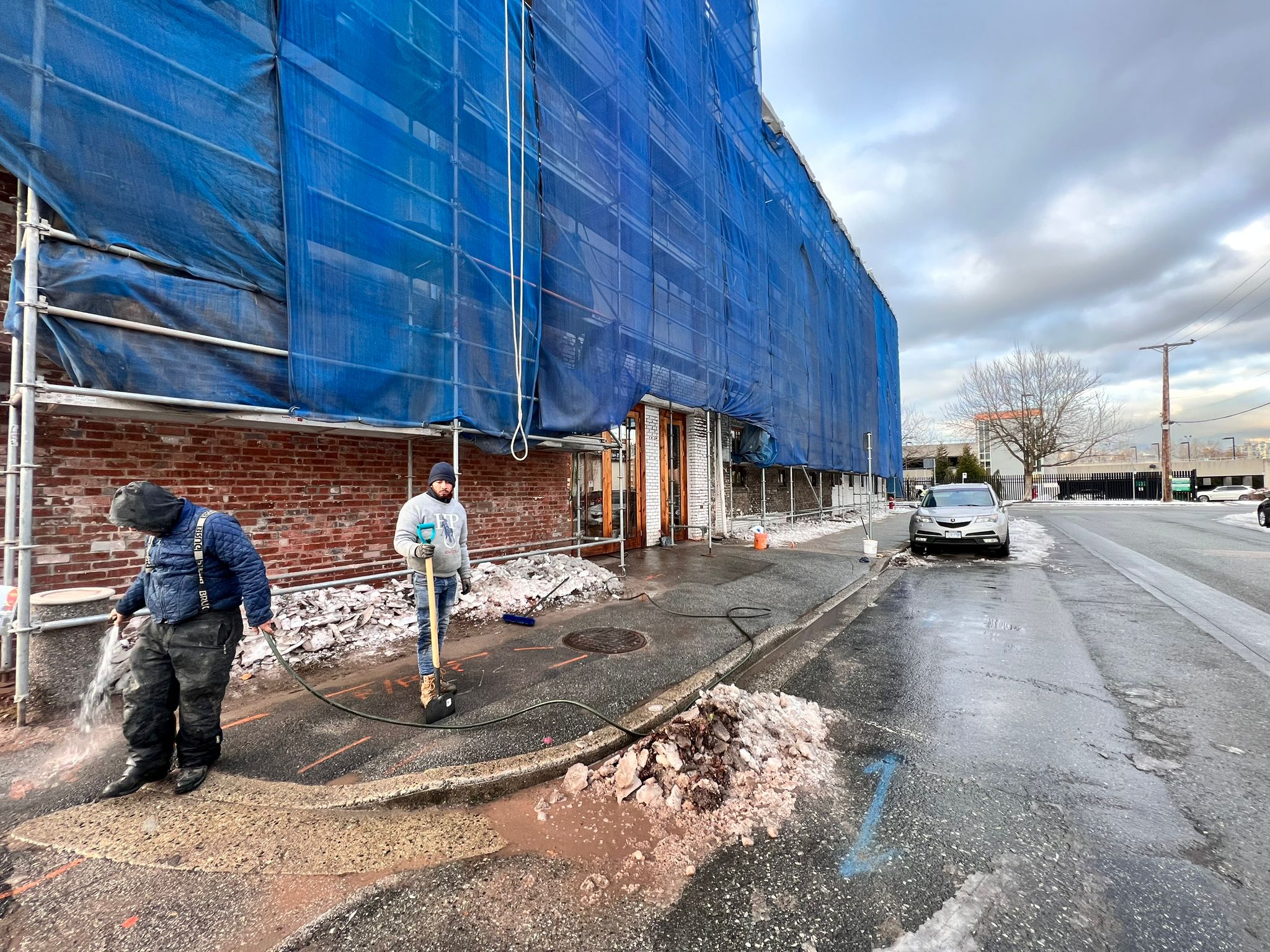 Crew clearing ice at the building entrance in winter — Living Spaces