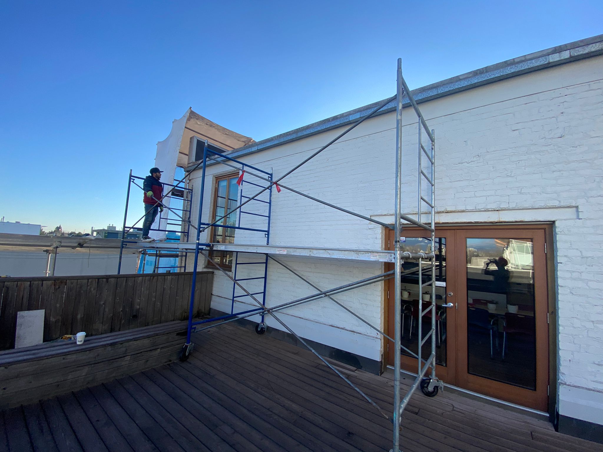 Mason working on rooftop scaffold against clear sky — Living Spaces