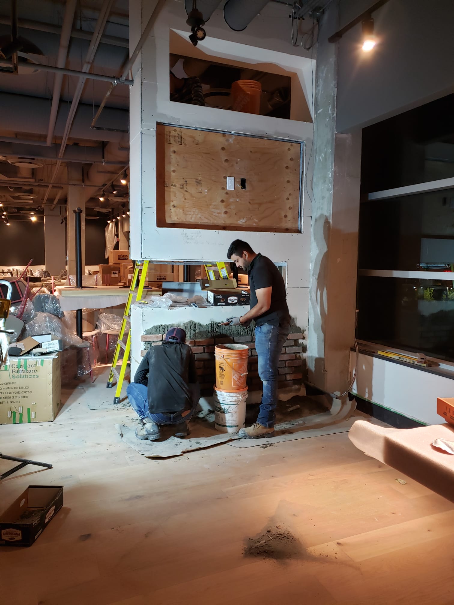 Masons building the brick fireplace surround — Tap & Barrel